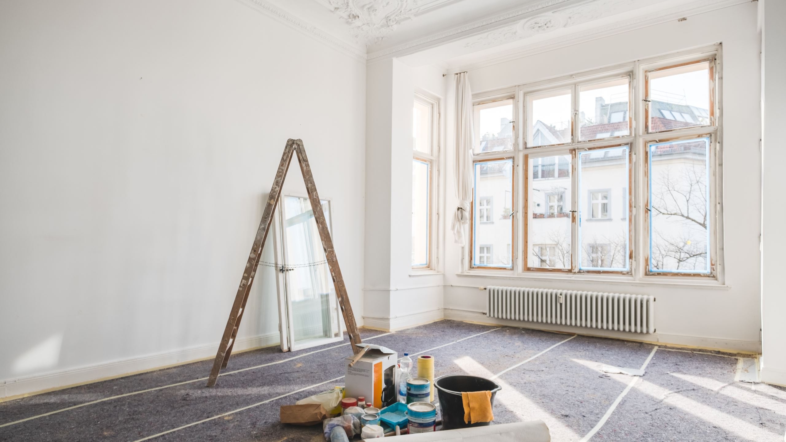 SWD Gebäudereinigung München bei der professionellen Baustellenreinigung – Mitarbeiter entfernt Bauschmutz in einem Neubau mit großen Fenstern und Betonboden. Gründliche Endreinigung für saubere Übergaben an Bauherren.