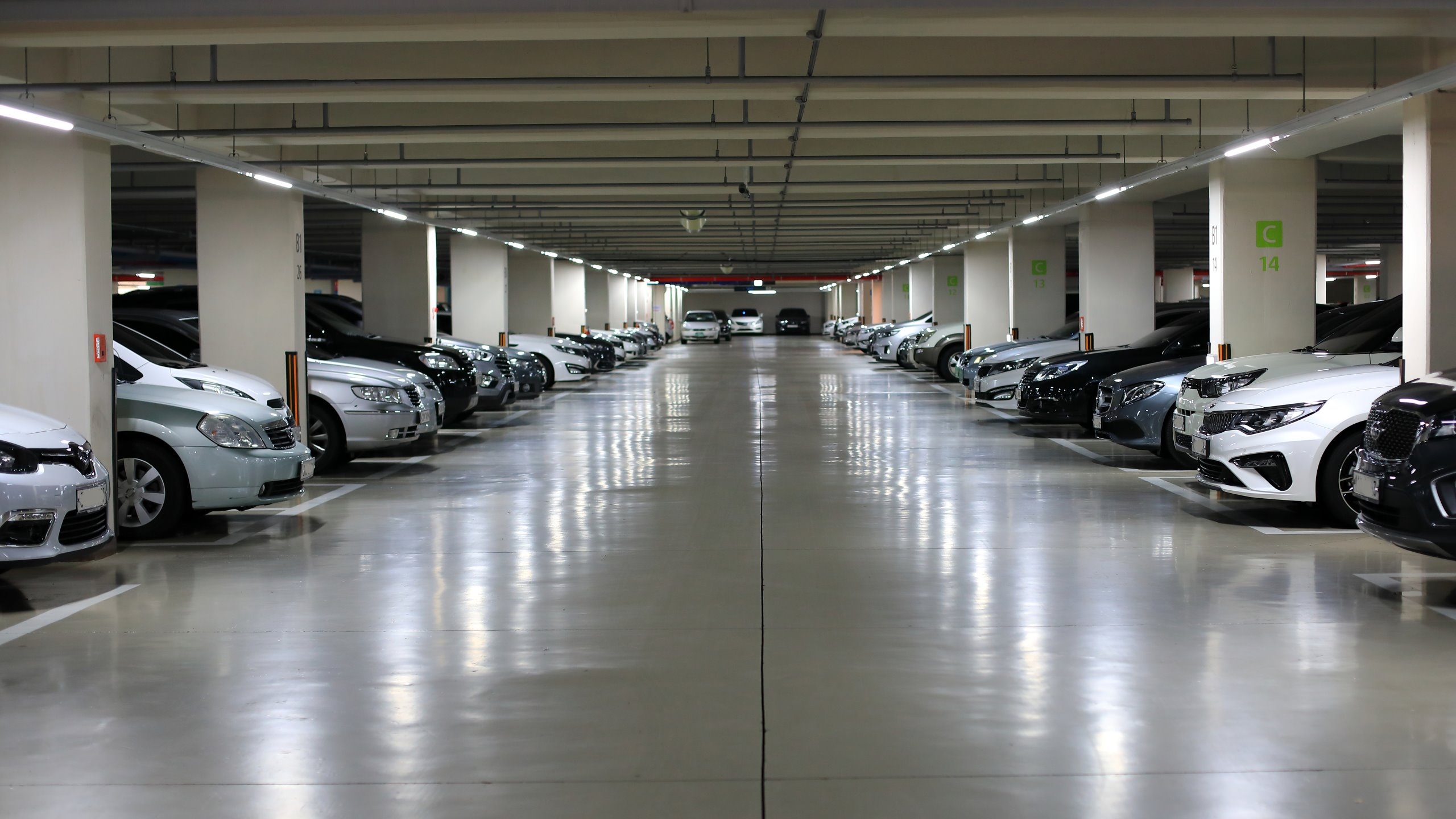 Mitarbeiter der SWD Gebäudereinigung München reinigt gründlich den Boden einer hellen Tiefgarage mit professionellem Reinigungsgerät – saubere, sichere Parkflächen durch regelmäßige Tiefgaragenreinigung..
